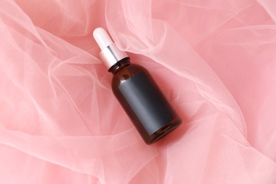Photo of Promotion. Bottle of cosmetic product on tulle cloth, top view