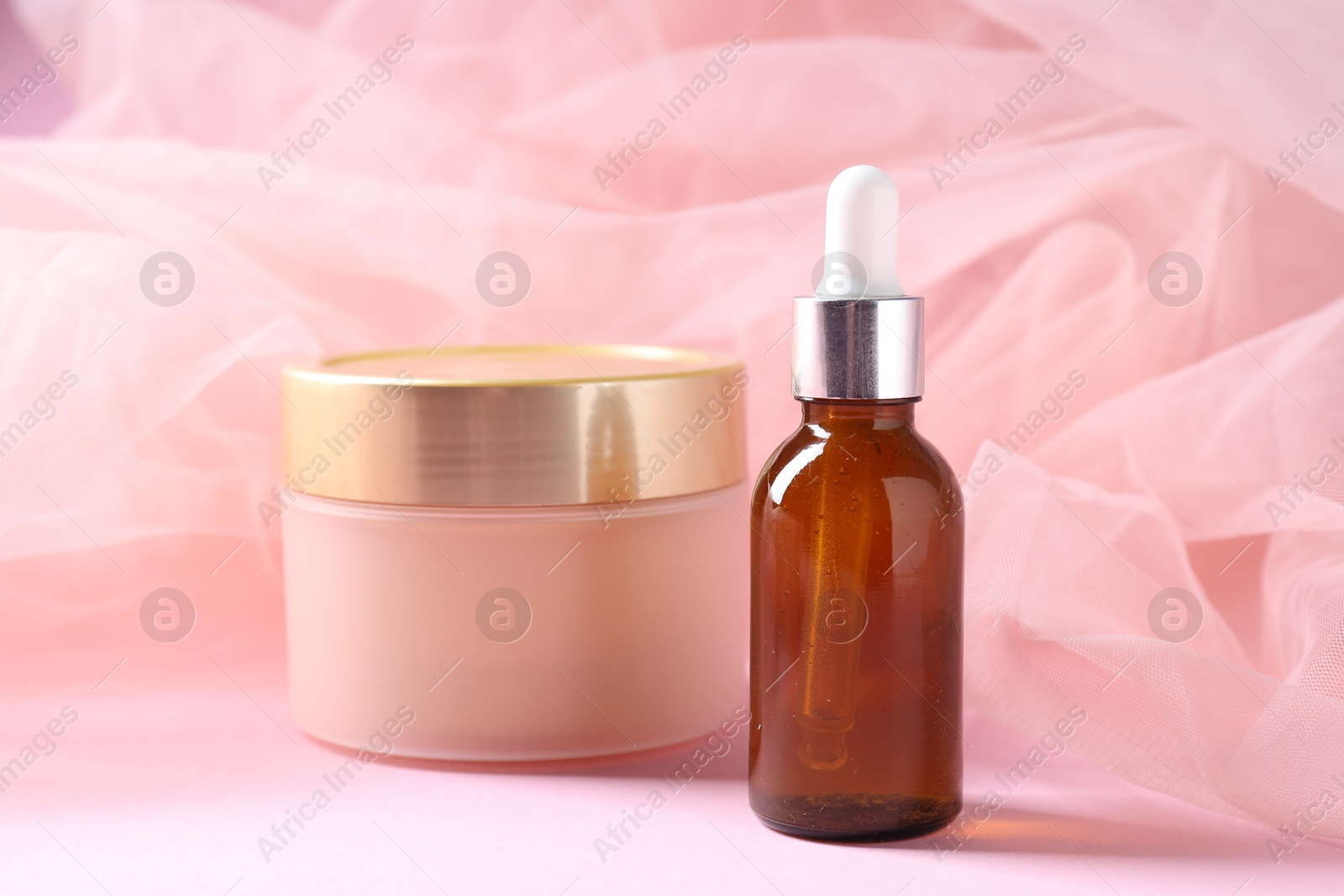 Promotion. Cosmetic products and tulle cloth on pink background, closeup Photo of Promotion. Cosmetic products and tulle cloth on pink background, closeup