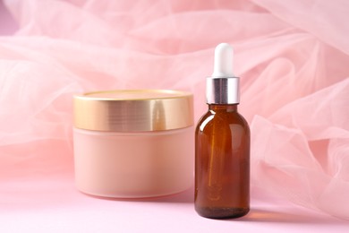 Photo of Promotion. Cosmetic products and tulle cloth on pink background, closeup