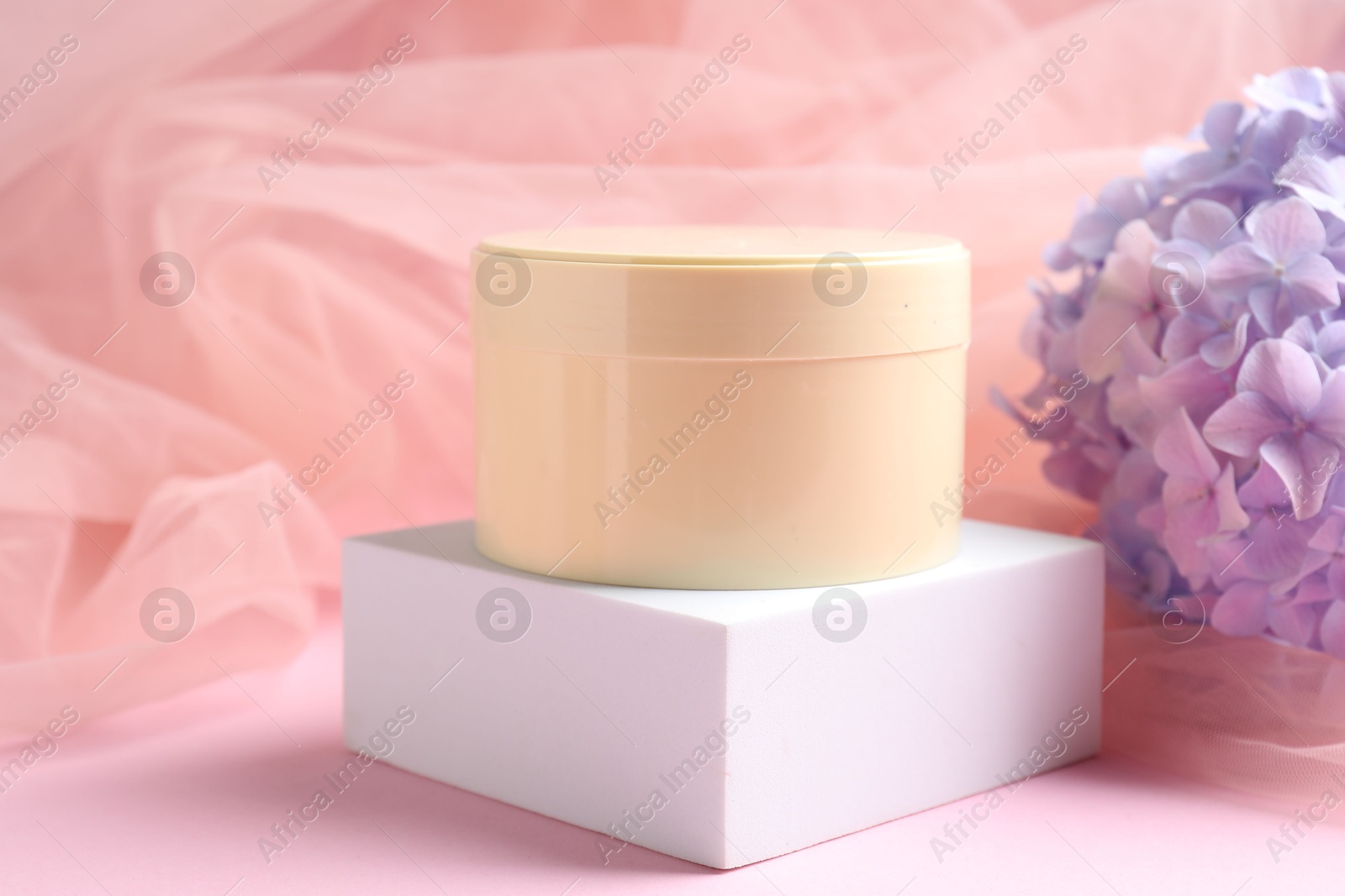 Promotion. Jar of cosmetic product, podium, hydrangea flowers and tulle cloth on pink background, closeup Photo of Promotion. Jar of cosmetic product, podium, hydrangea flowers and tulle cloth on pink background, closeup
