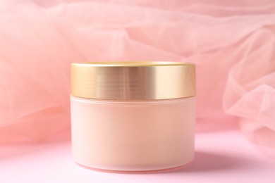 Photo of Promotion. Jar of cosmetic product and tulle cloth on pink background, closeup
