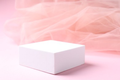 Photo of Promotion. Podium for product presentation and tulle cloth on pink background, closeup