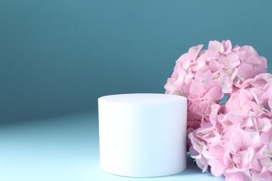 Photo of Promotion. Podium for product presentation and hydrangea flowers on light blue background, closeup