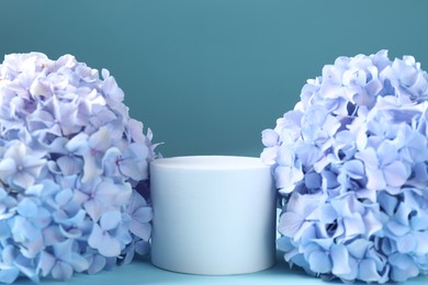Photo of Promotion. Podium for product presentation and hydrangea flowers on light blue background, closeup