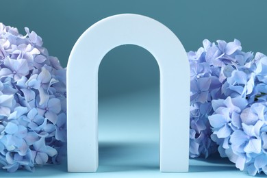 Photo of Promotion. White figure and hydrangea flowers on light blue background, closeup