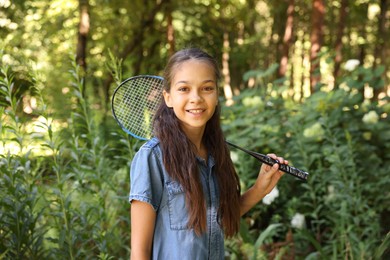 Photo of Portrait of smiling little girl with badminton racket in park