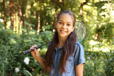 Photo of Portrait of smiling little girl with badminton racket in park