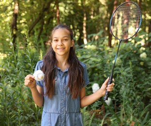 Photo of Portrait of smiling little girl with badminton racket and shuttlecock in park