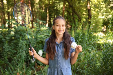 Photo of Portrait of smiling little girl with badminton racket and shuttlecock in park