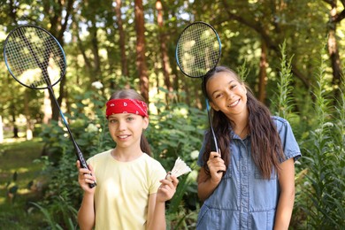 Photo of Portrait of smiling little girls with badminton rackets and shuttlecock in park