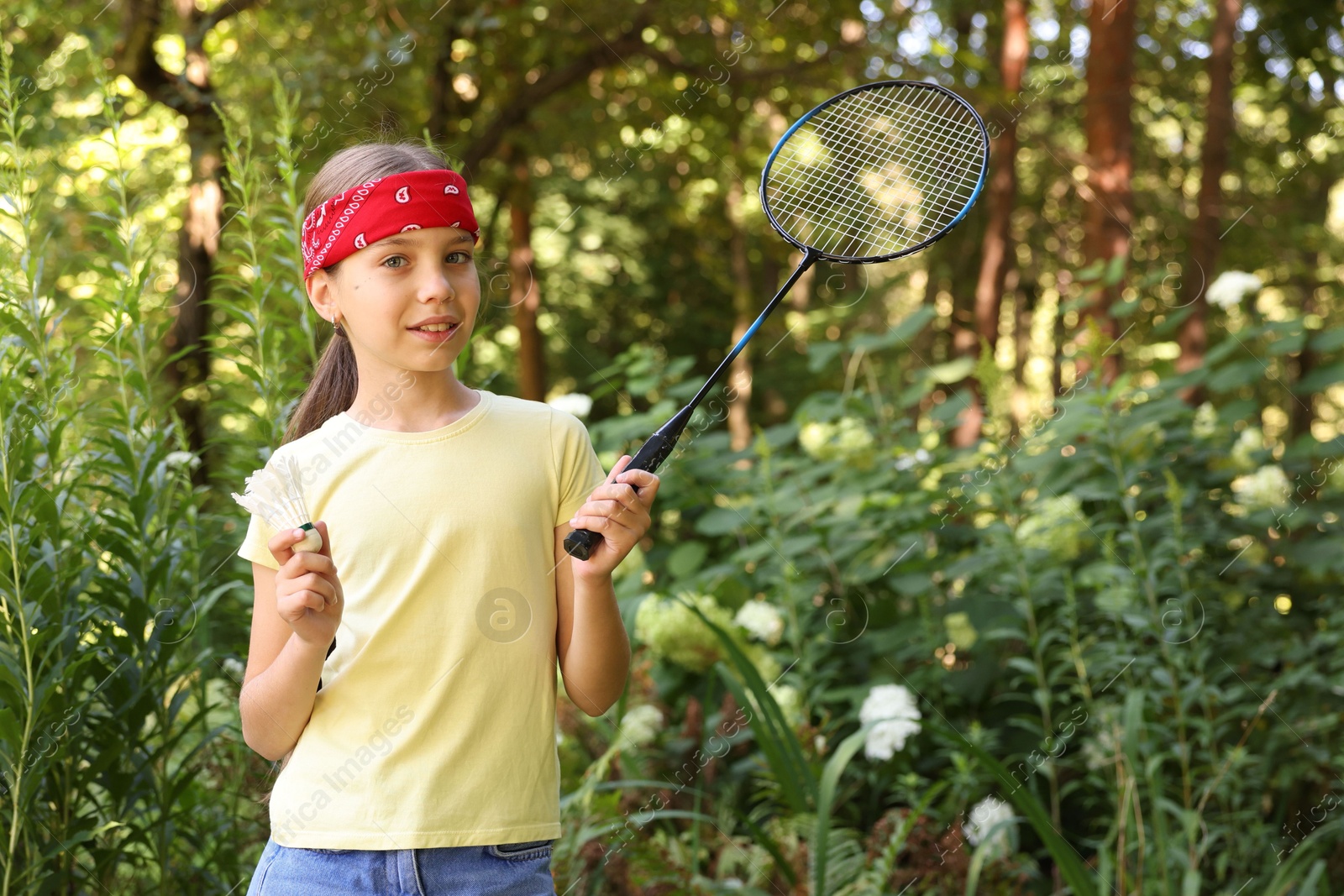 Portrait of smiling little girl in bandana with badminton racket and shuttlecock in park Photo of Portrait of smiling little girl in bandana with badminton racket and shuttlecock in park