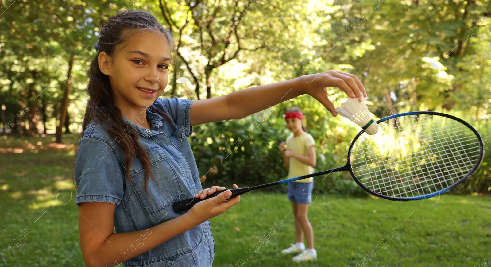 Smiling little girl with badminton racket and shuttlecock playing with her friend in park, selective focus Photo of Smiling little girl with badminton racket and shuttlecock playing with her friend in park, selective focus