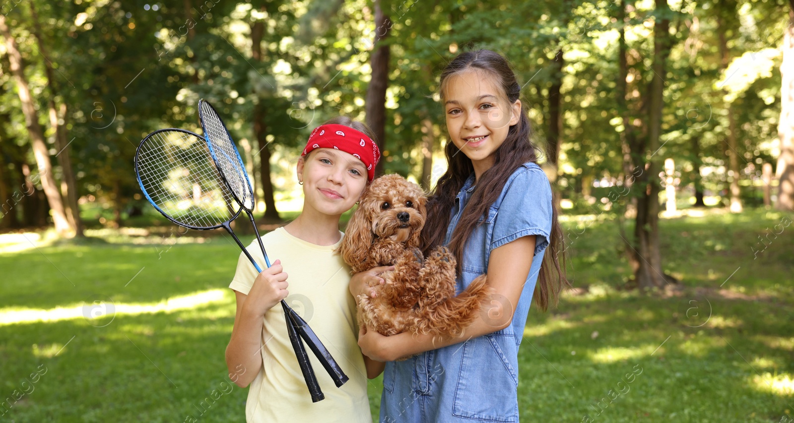 Portrait of cute little girls with badminton rackets and dog in park Photo of Portrait of cute little girls with badminton rackets and dog in park