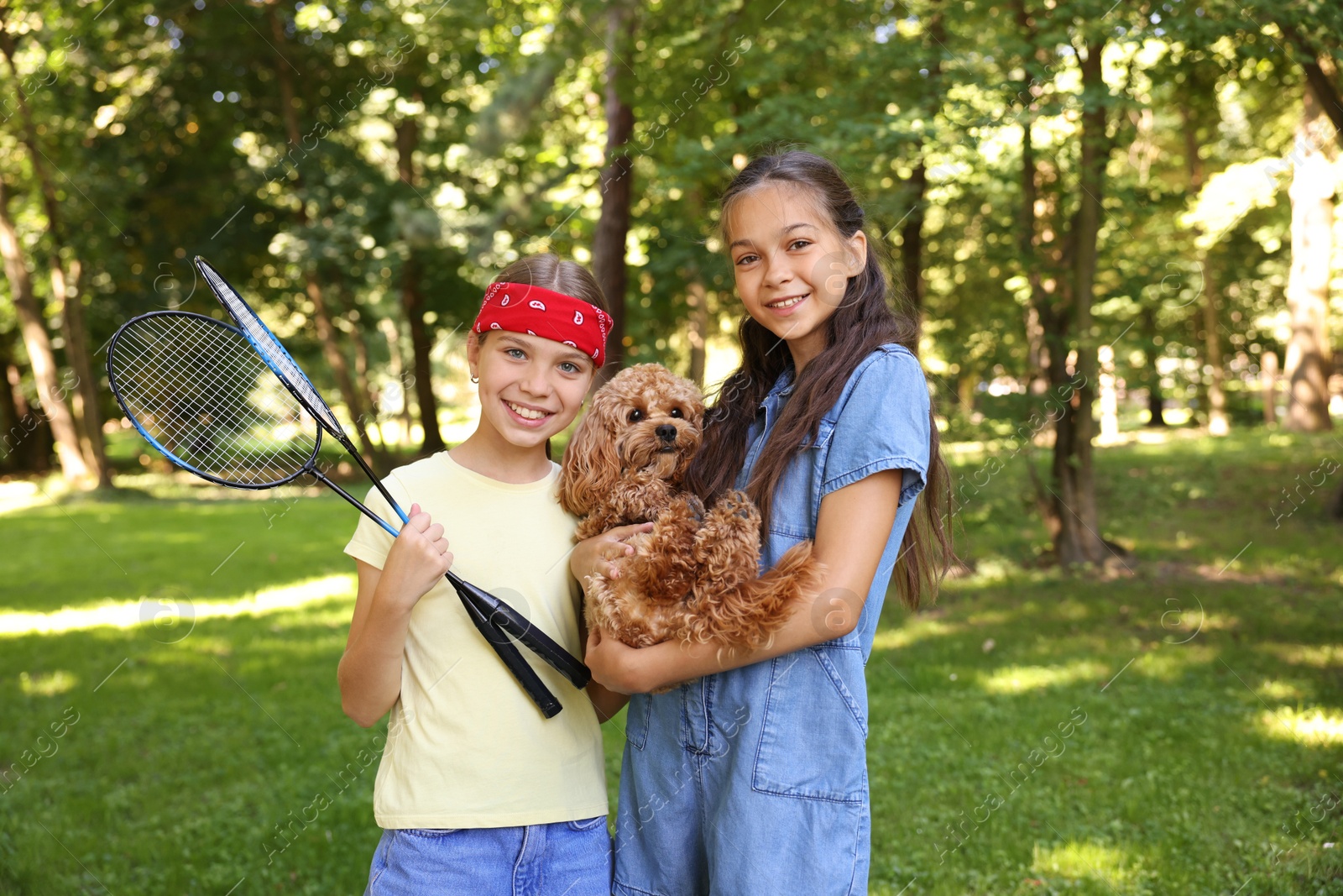 Portrait of cute little girls with badminton rackets and dog in park Photo of Portrait of cute little girls with badminton rackets and dog in park