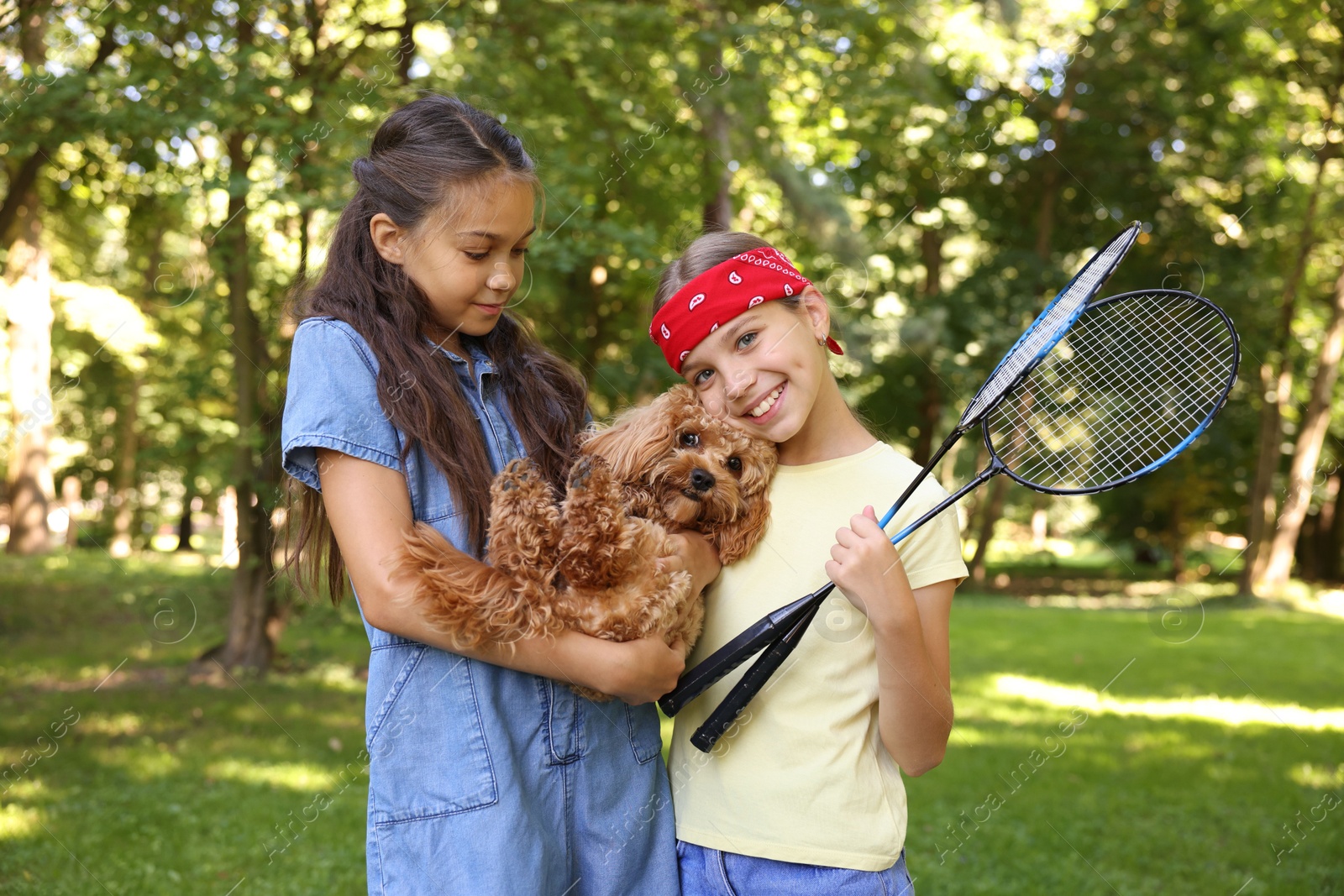 Cute little girls with badminton rackets and dog in park Photo of Cute little girls with badminton rackets and dog in park