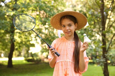 Photo of Portrait of smiling little girl in hat with badminton racket and shuttlecock in park