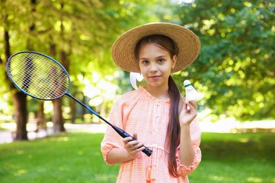 Photo of Portrait of cute little girl in hat with badminton racket and shuttlecock in park
