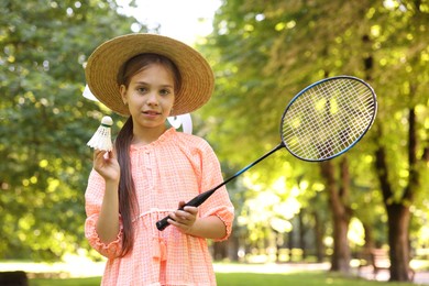 Photo of Portrait of smiling little girl in hat with badminton racket and shuttlecock in park