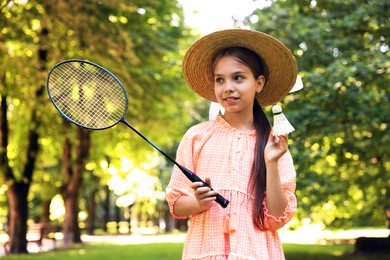 Photo of Smiling little girl in hat with badminton racket and shuttlecock in park