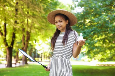 Photo of Smiling little girl in hat with badminton racket and shuttlecock in park