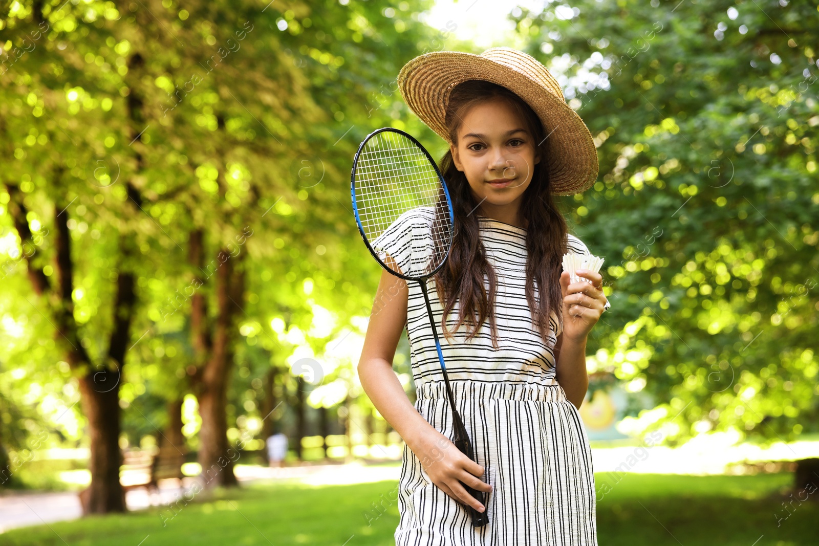 Cute little girl in hat with badminton racket and shuttlecock in park. Space for text Photo of Cute little girl in hat with badminton racket and shuttlecock in park. Space for text