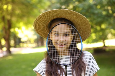 Photo of Smiling little girl in hat with badminton racket in park