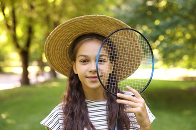 Photo of Smiling little girl in hat with badminton racket in park