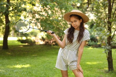 Photo of Portrait of cute little girl in hat with badminton racket in park