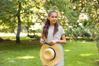 Photo of Portrait of cute little girl with badminton racket and hat in park