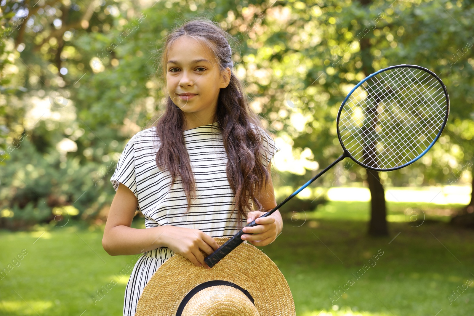 Portrait of cute little girl with badminton racket and hat in park Photo of Portrait of cute little girl with badminton racket and hat in park