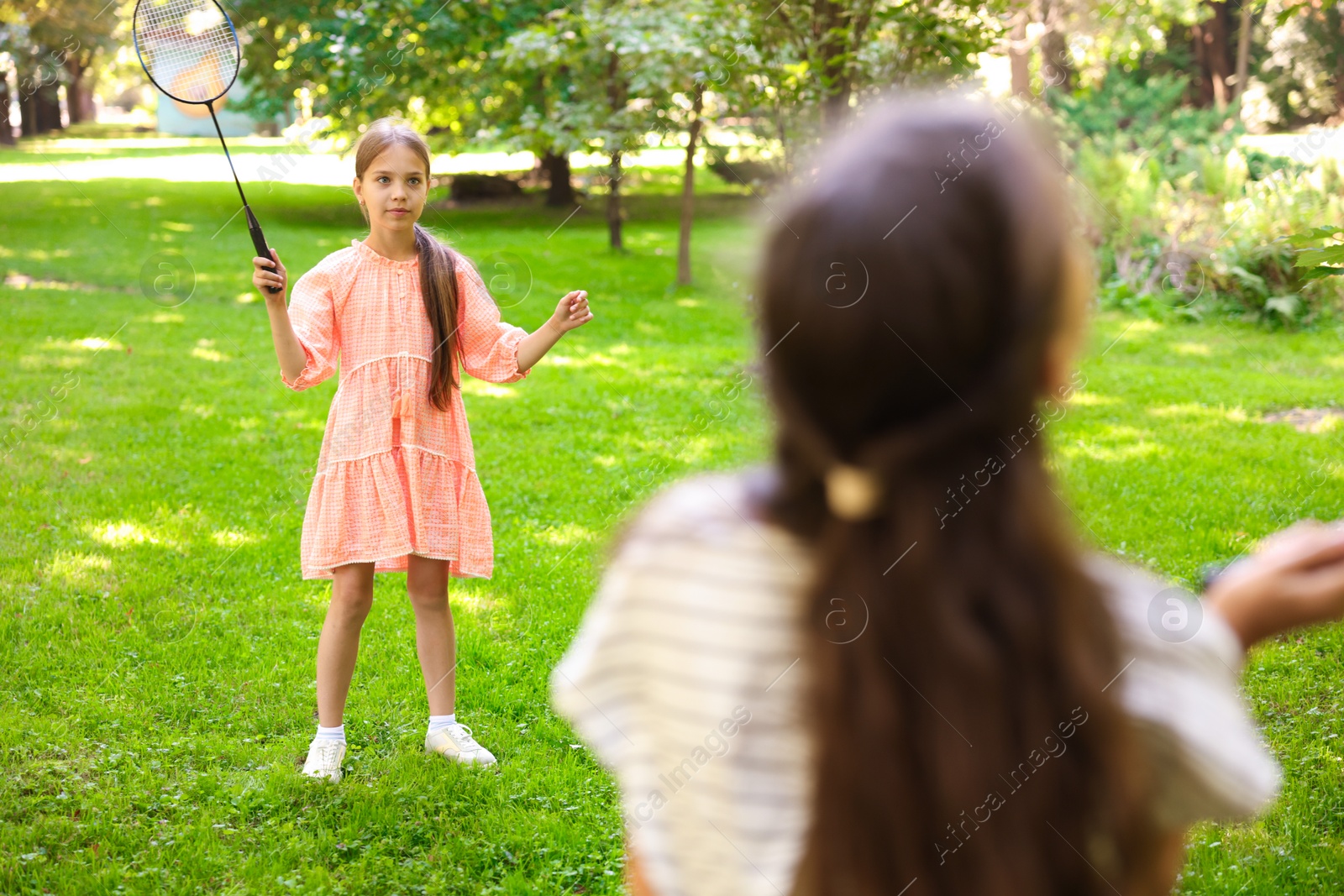 Cute little girls playing badminton in park, selective focus Photo of Cute little girls playing badminton in park, selective focus