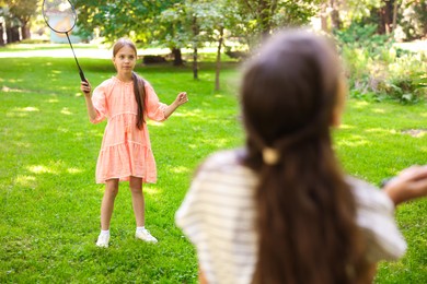 Photo of Cute little girls playing badminton in park, selective focus