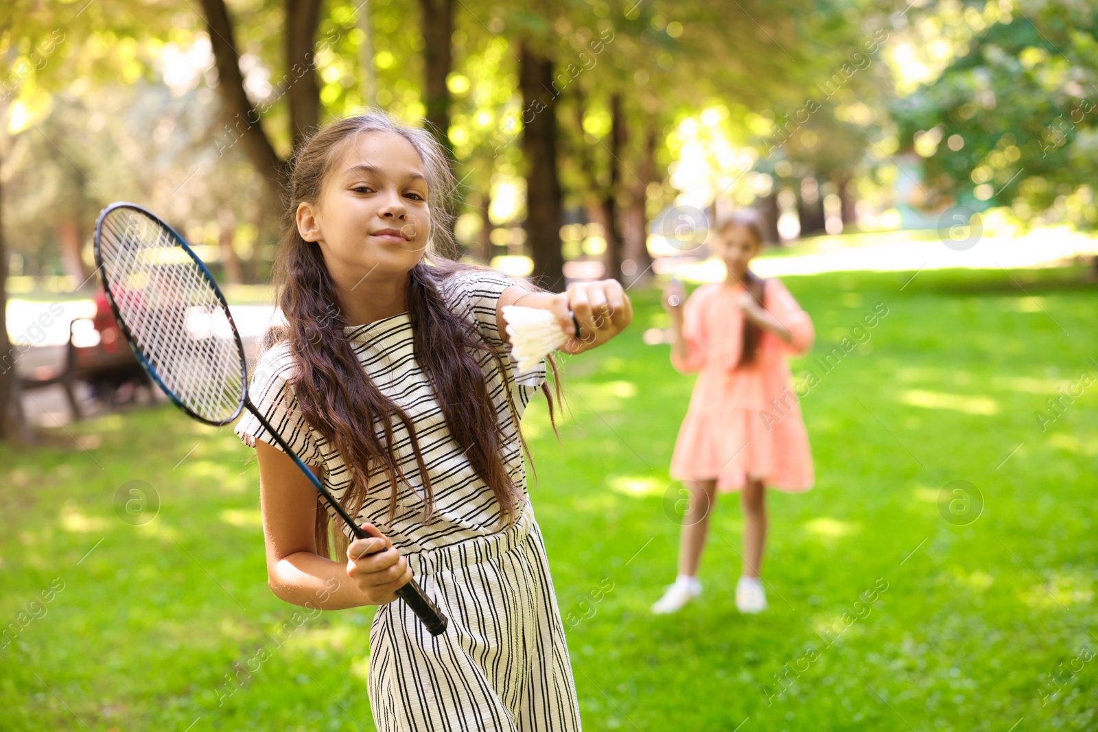 Cute little girl with badminton racket and shuttlecock playing with her friend in park, selective focus Photo of Cute little girl with badminton racket and shuttlecock playing with her friend in park, selective focus