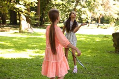 Photo of Cute little girls playing badminton in park, selective focus