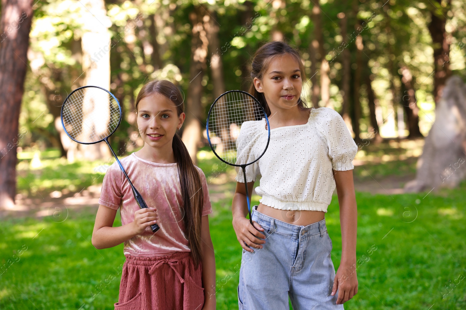 Portrait of smiling little girls with badminton rackets in park Photo of Portrait of smiling little girls with badminton rackets in park