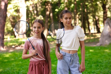 Photo of Portrait of smiling little girls with badminton rackets in park
