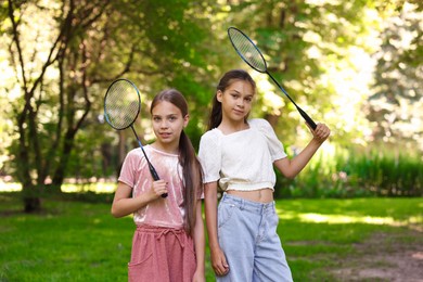 Photo of Portrait of smiling little girls with badminton rackets in park