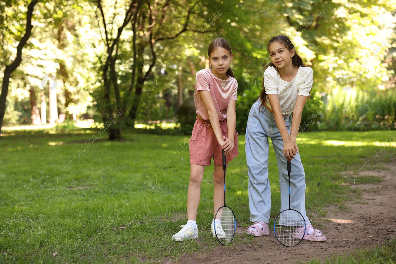 Cute little girls with badminton rackets posing in park. Space for text Photo of Cute little girls with badminton rackets posing in park. Space for text
