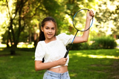 Photo of Portrait of smiling little girl with badminton racket in park