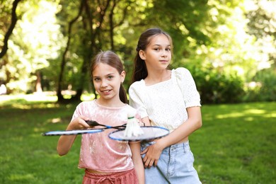 Photo of Portrait of smiling little girls with badminton rackets and shuttlecock in park