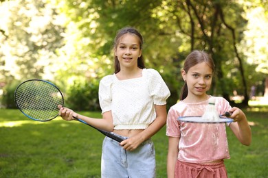 Photo of Portrait of smiling little girls with badminton rackets and shuttlecock in park