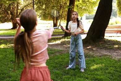 Photo of Cute little girls playing badminton in park, selective focus