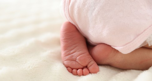 Photo of Cute newborn baby lying on bed, closeup. Space for text