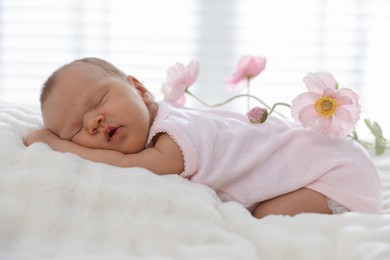 Photo of Cute newborn baby sleeping on bed and flowers indoors