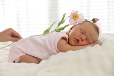 Photo of Mother with her cute newborn baby and flowers on bed indoors, closeup