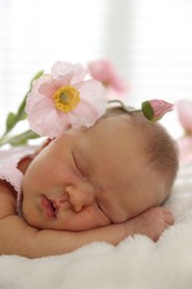 Photo of Cute newborn baby sleeping on bed and flowers indoors