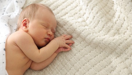 Photo of Cute newborn baby sleeping on bed, top view. Space for text