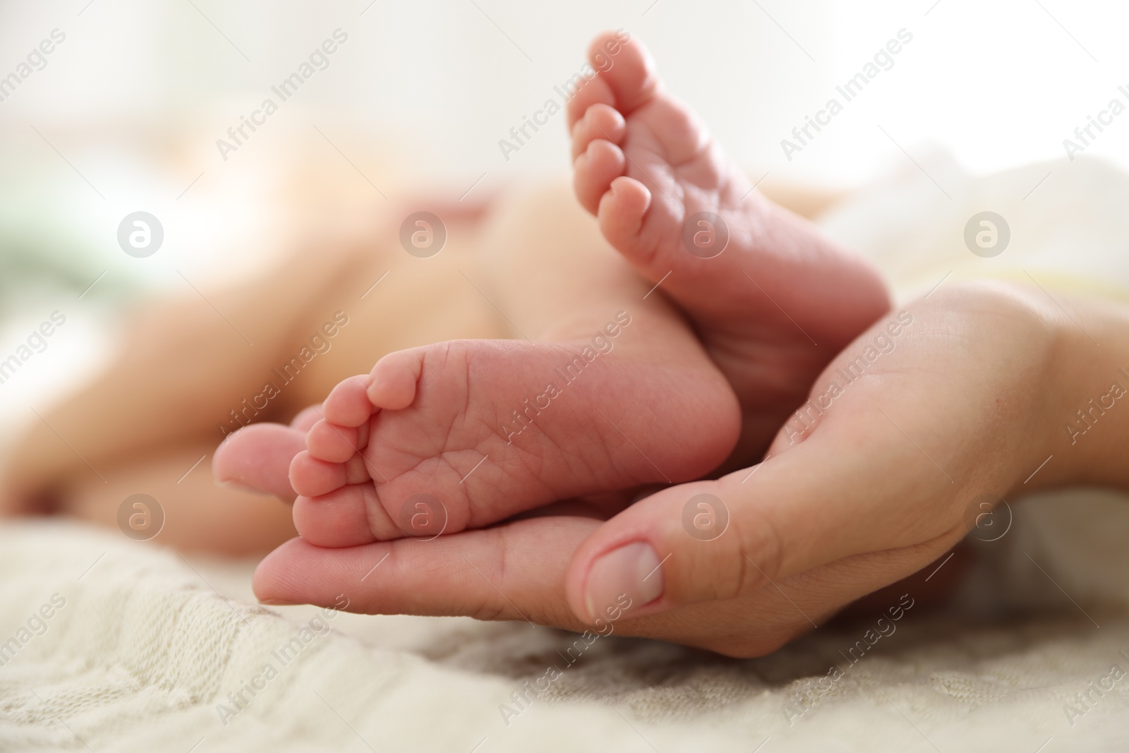 Mother with her cute newborn baby on bed indoors, closeup Photo of Mother with her cute newborn baby on bed indoors, closeup