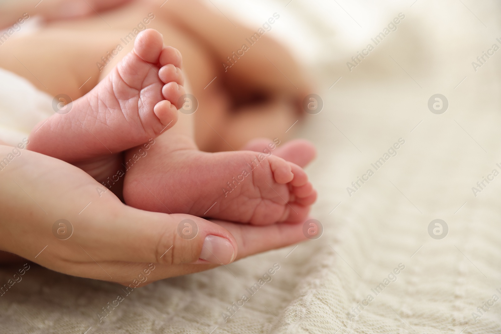 Mother with her cute newborn baby on bed indoors, closeup. Space for text Photo of Mother with her cute newborn baby on bed indoors, closeup. Space for text