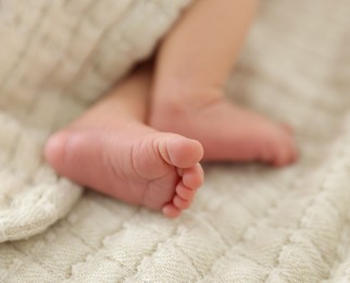 Photo of Cute newborn baby lying on bed indoors, closeup
